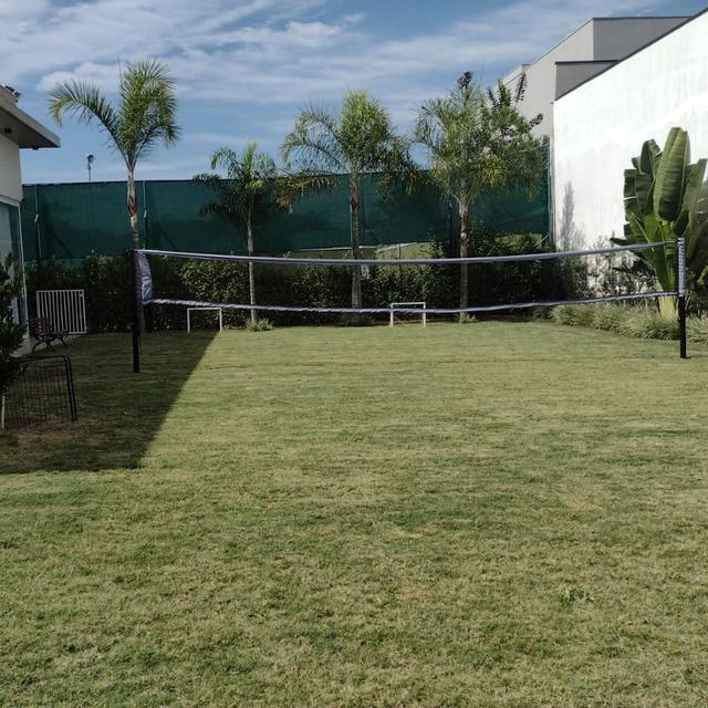 Gramado amplo aparado ao lado de uma casa, com palmeiras ao fundo